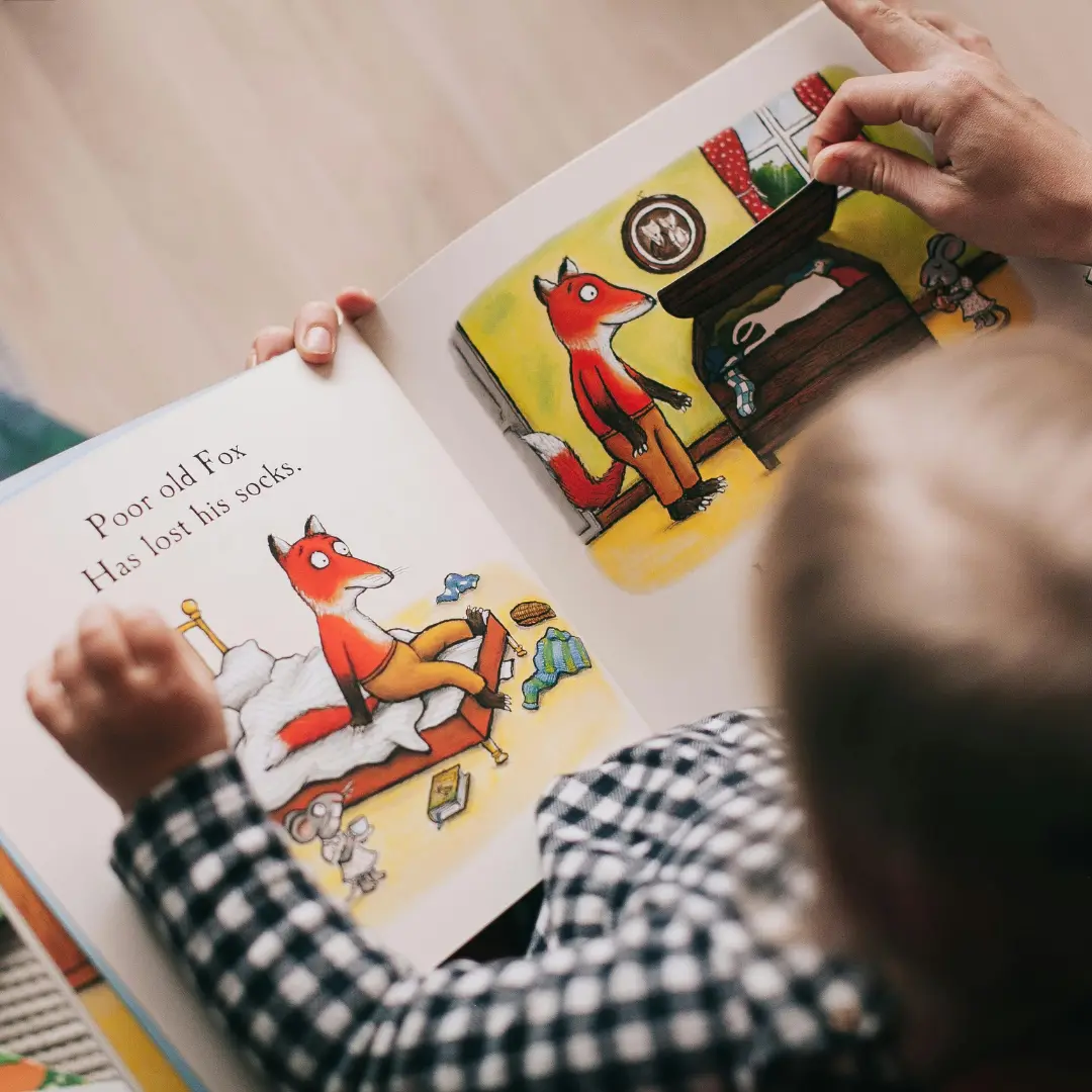 Un bambino che legge un libro illustrato con una volpe.