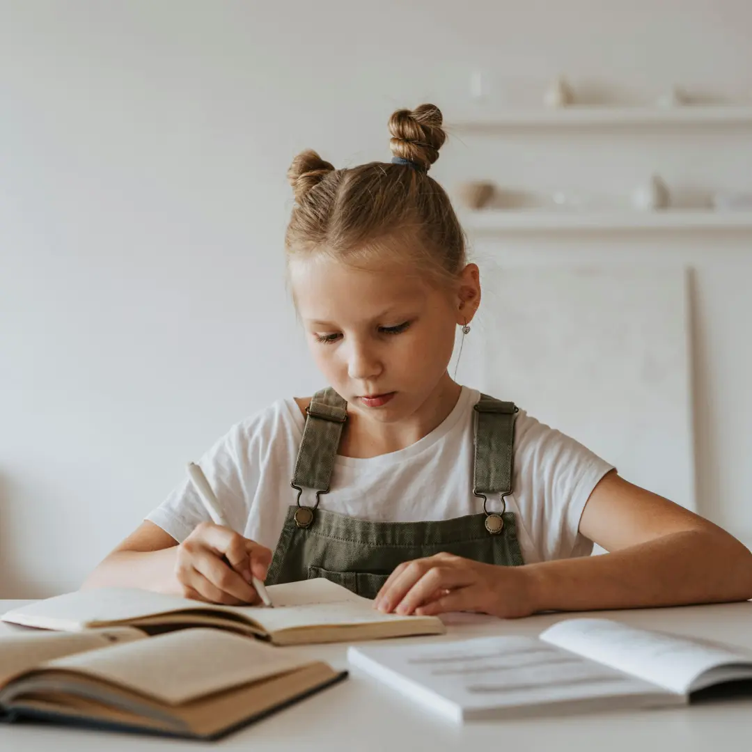 Ragazza che scrive in un quaderno mentre studia.
